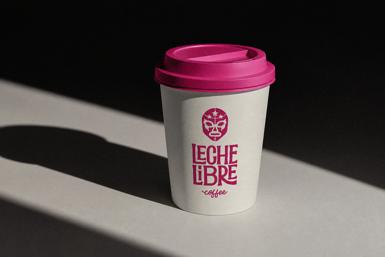 Leche Libre Coffee takeaway cup with bright pink branding against a dark background